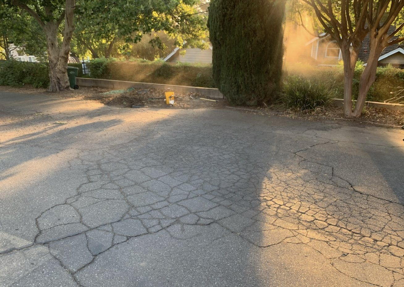 Older asphalt before treatment — heavy surface cracking and fading